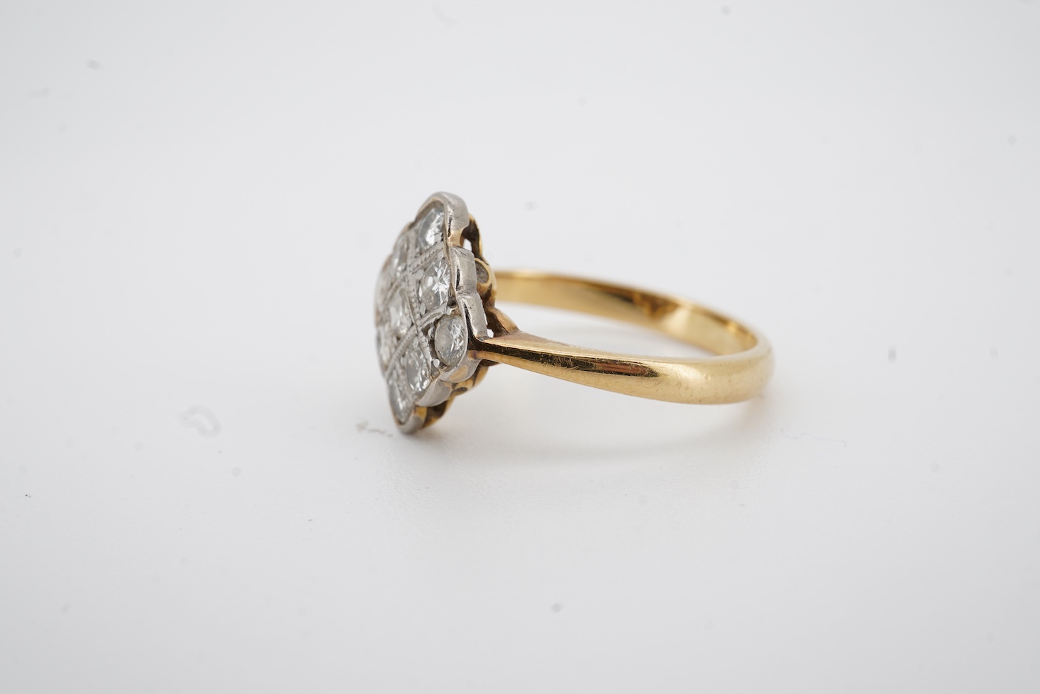 A yellow metal and nine stone millegrain set diamond cluster ring, of diamond form, size M, gross weight 2.9 grams.